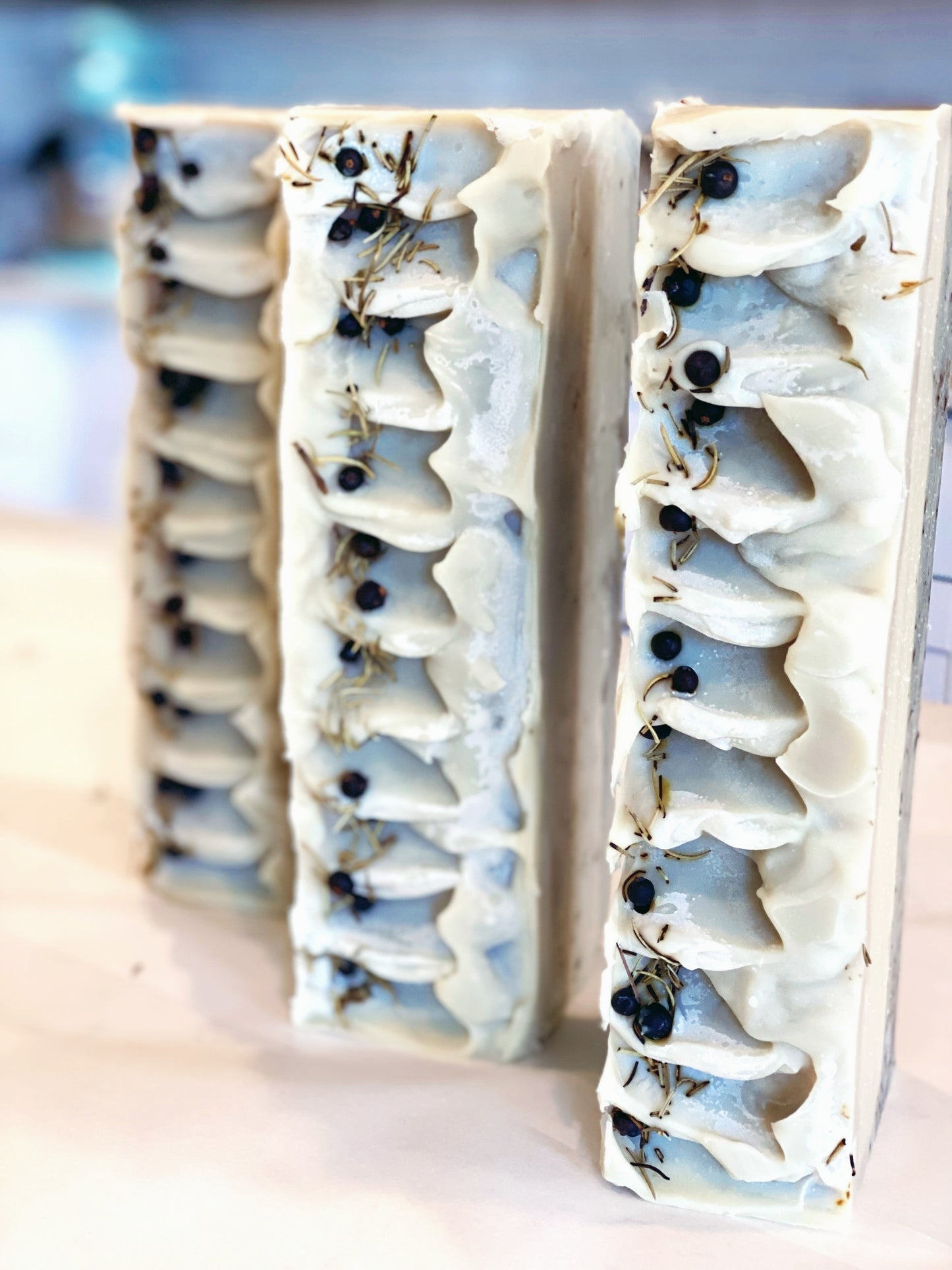 three loaves of l'etoile du nord soap standing vertically on a white countertop in a white kitchen.