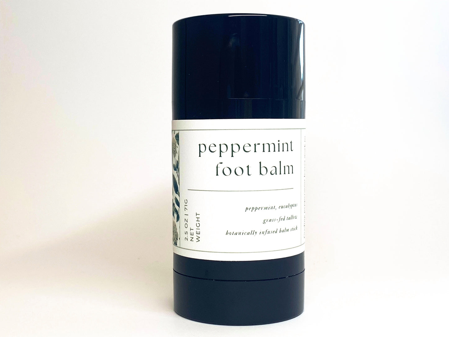black tube of peppermint foot balm stick against a white backdrop.