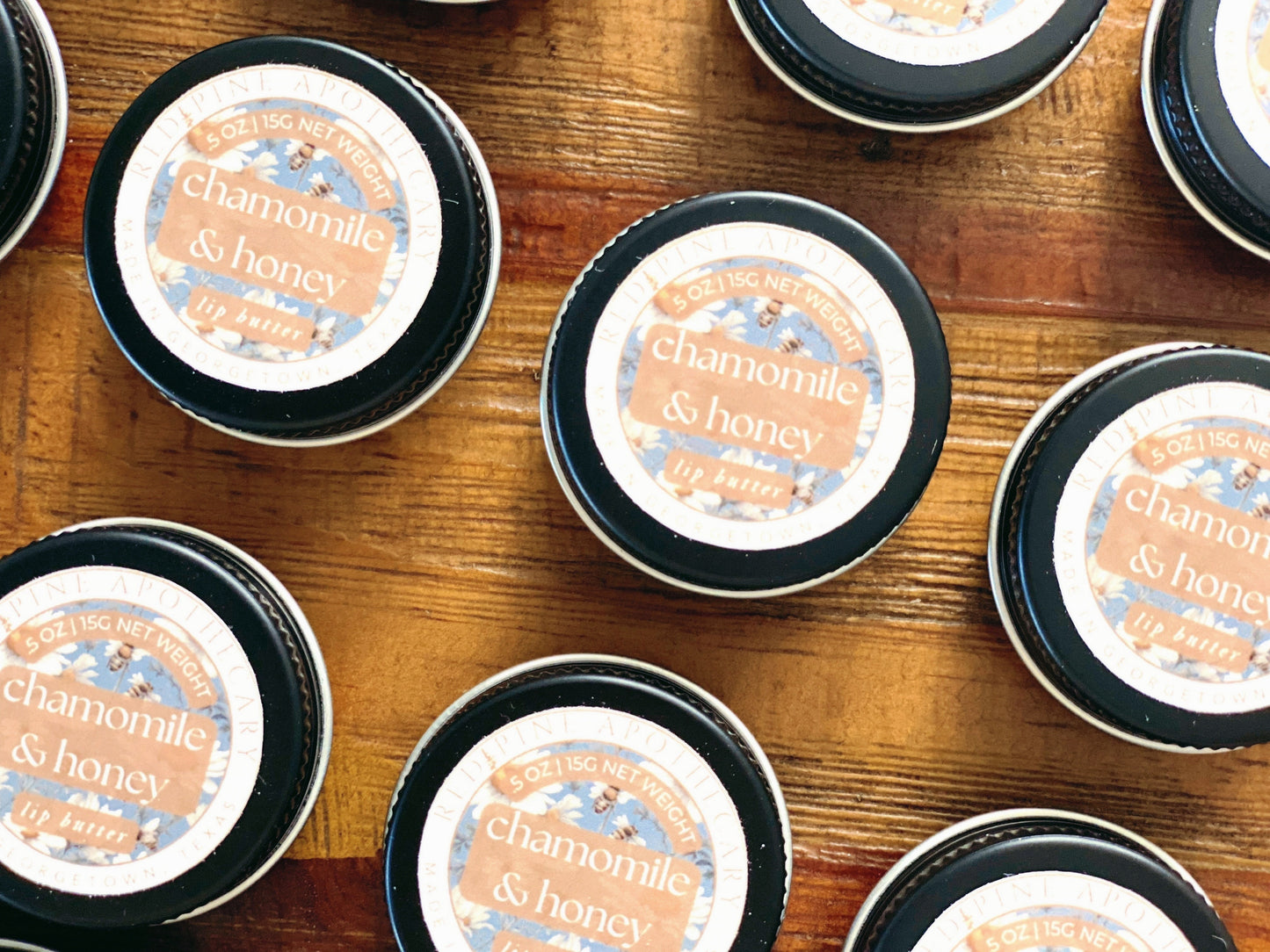 zoomed in flat lay of chamomile and honey lip butter on a wooden table