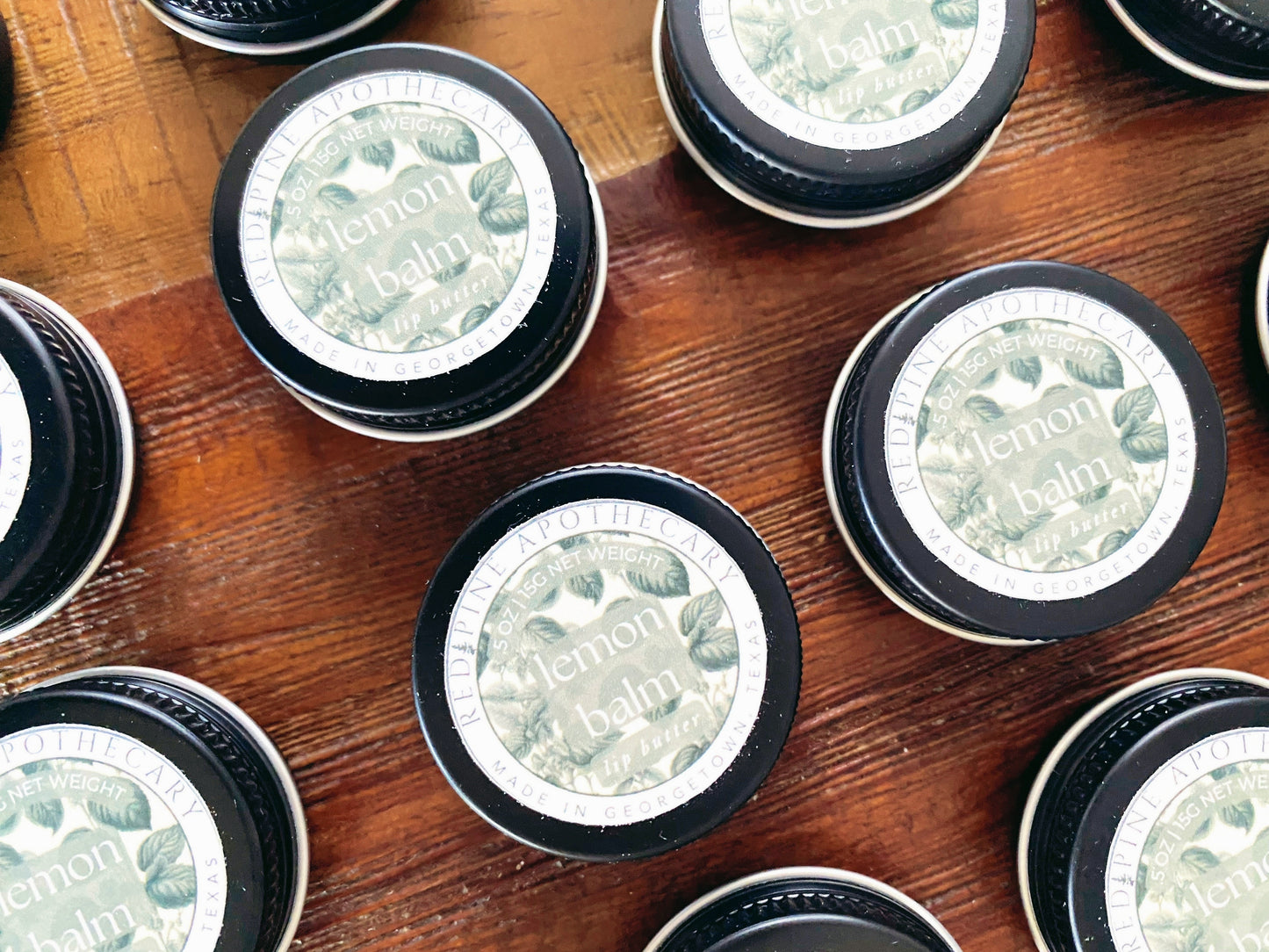zoomed in flat lay of lemon balm lip butter on a wooden table.